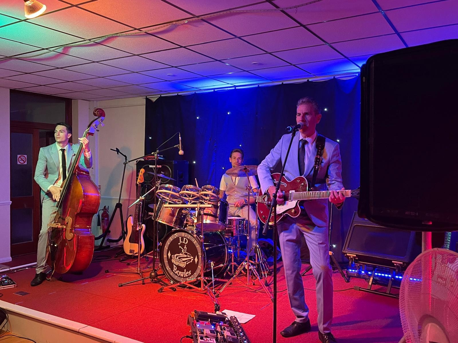 Full band on stage with red and blue lighting